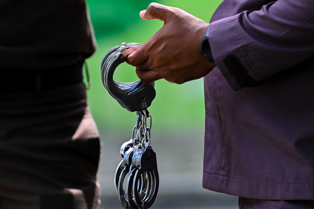Petugas penegak hukum memegang borgol saat pelaksanaan hukuman cambuk di depan umum di Banda Aceh pada Kamis (21/5/2026). Foto: Chaideer Mahyuddin/AFP