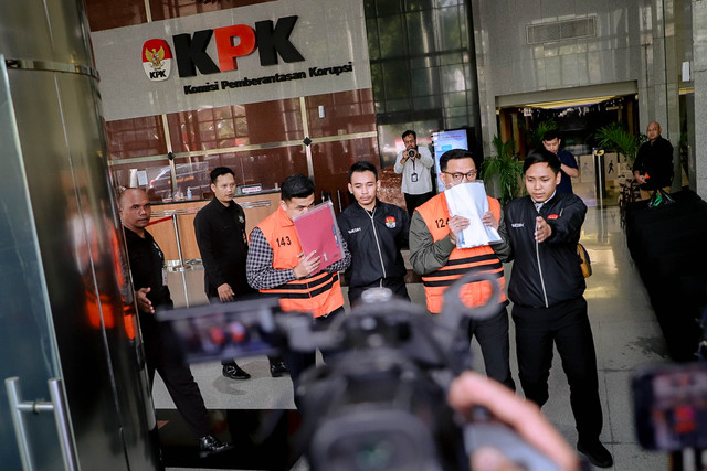 Kepala Kantor Imigrasi Jakarta Barat Ronald Arman Abdullah (kanan) mengenakan baju tahanan berjalan menuju mobil tahanan usai menjalani pemeriksaan di Gedung Merah Putih KPK, Jakarta, Kamis (4/6/2026). Foto: Jamal Ramadhan/kumparan