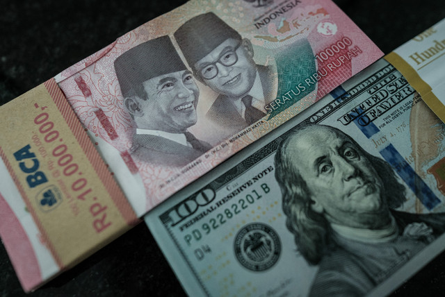 Sejumlah uang kertas pecahan 100.000 rupiah Indonesia difoto di samping uang kertas pecahan 100 dolar AS di sebuah tempat penukaran mata uang di Jakarta, Kamis (4/6/2026). Foto: Yasuyoshi Chiba/AFP