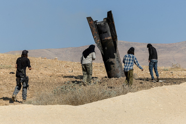 Para pemukim Israel berdiri di samping bagian rudal yang mencuat dari tanah, setelah serangan dari Iran, di Tepi Barat bagian tengah yang diduduki Israel, Senin (8/6/2026). Foto: Naama Stern/REUTERS