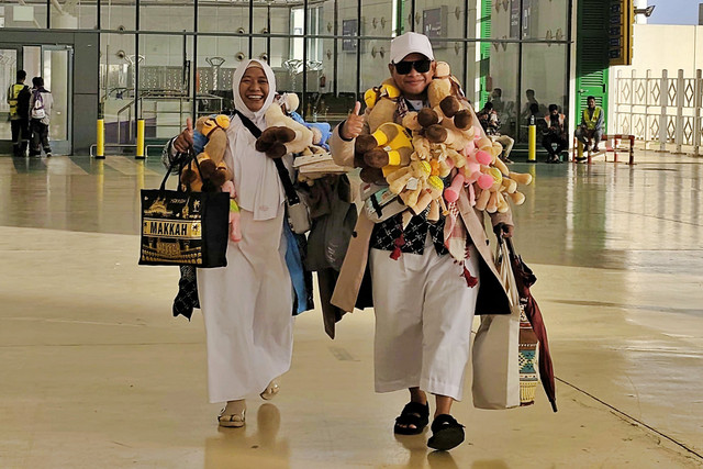Haji Core 2026, sejumlah jemaah haji berjalan sambil mengalungkan boneka unta yang menjadi primadona oleh-oleh bagi sanak keluarga di Indonesia. Foto: Dok. MCH 2026