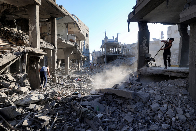 Seorang anak laki-laki menyapu puing-puing bangunan yang hancur akibat serangan Israel di kamp pengungsi Palestina Maghazi, Jalur Gaza tengah, Jumat (12/6/2026). Foto: Eyad BABA / AFP