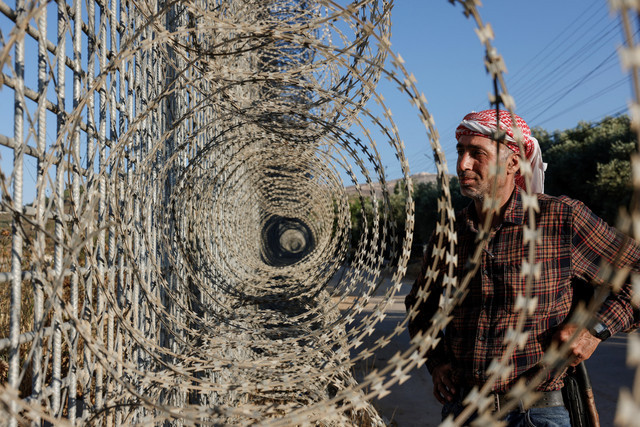 Petani Palestina berusia 40 tahun, Mohammad Fuqaha, berdiri di dekat pagar yang didirikan Israel yang mengelilingi kota Sinjil, di utara Ramallah di Tepi Barat Palestina yang diduduki Israel, Senin (15/6/2026). Foto: Zain Jaafar/AFP