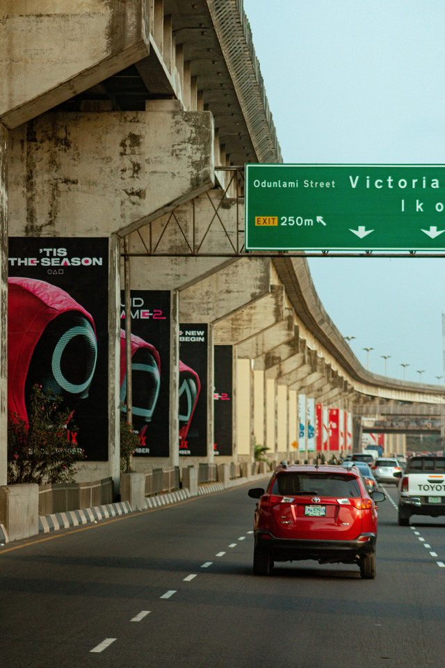 Poster Serial Squid Game (Gambar dari Victor Chijioke/Pexels) Photo by Victor Chijioke from Pexels: https://www.pexels.com/photo/urban-expressway-in-lagos-with-billboards-29812611/