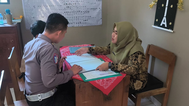 Anggota Satlantas Polres Kudus mendampingi siswa yatim piatu mengambil rapor di SMP Negeri 2 Gebog, Kabupaten Kudus, Jawa Tengah pada Sabtu (20/6/2026). Foto: Dok. Polres Kudus