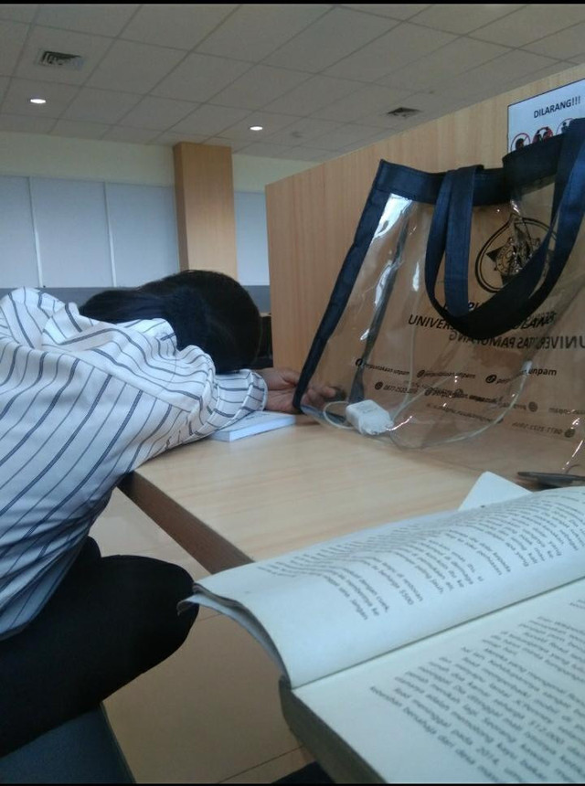 Ketiduran di perpustakaan kampus sambil memeluk buku. Sumber foto: Dokumentasi pribadi.