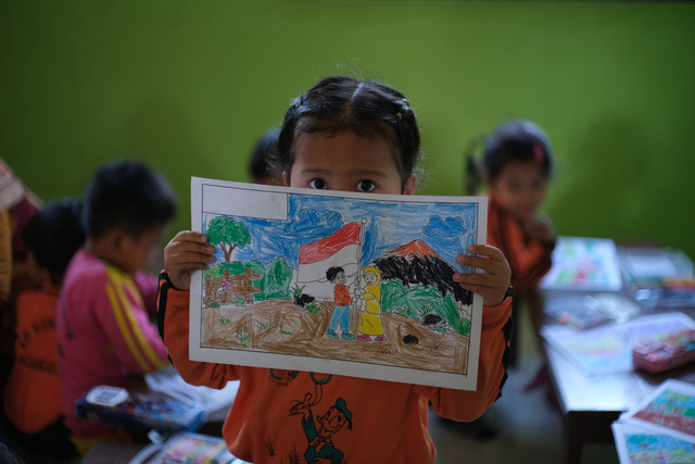 Foto Seorang Anak Memegang Hasil Gambarnya, Sumber: Pexels.com