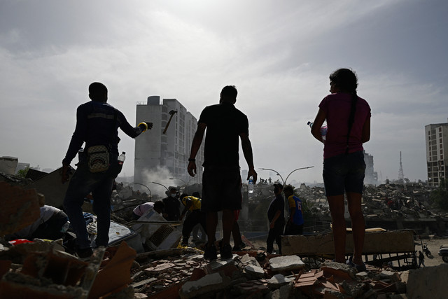 Warga berdiri di antara puing-puing bangunan setelah gempa bumi melanda Caraballeda, negara bagian La Guaira, sekitar 40 kilometer timur laut Caracas, Venezuela, Kamis (25/6/2026). Foto: Federico Parra/AFP