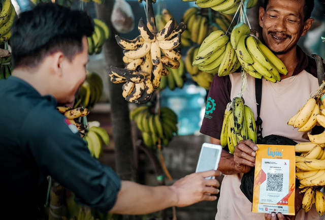Ilustrasi masyarakat dan pedagang bertransaksi menggunakan QRIS dari aplikasi Livin' by Mandiri. Foto: Dok. Bank Mandiri