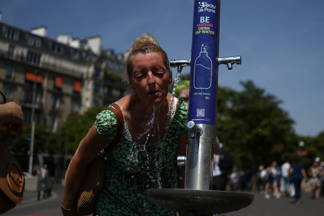 Seorang wanita mendinginkan diri di air mancur umum dekat Place du Trocadero saat suhu tinggi di tengah gelombang panas di Paris, Prancis, Jumat (27/6/2026). Foto: Tom Nicholson/REUTERS