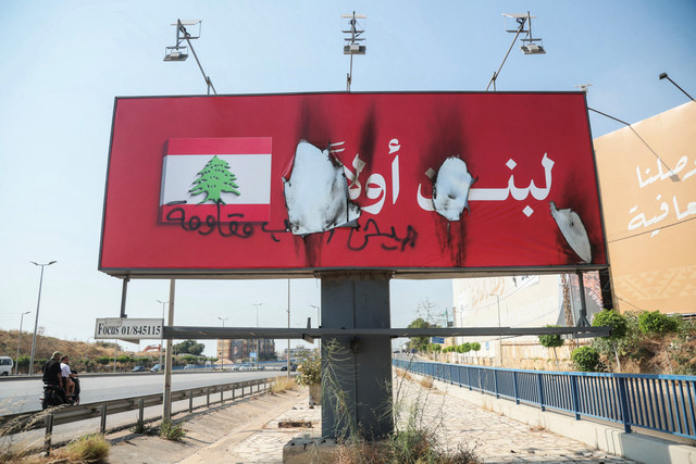 Papan reklame bertuliskan dalam bahasa Arab "Lebanon yang utama" setelah dirusak dan dibakar di sepanjang jalan bandara Beirut, Lebanon, Minggu (28/6/2026). Foto: Ibrahim AMRO/AFP