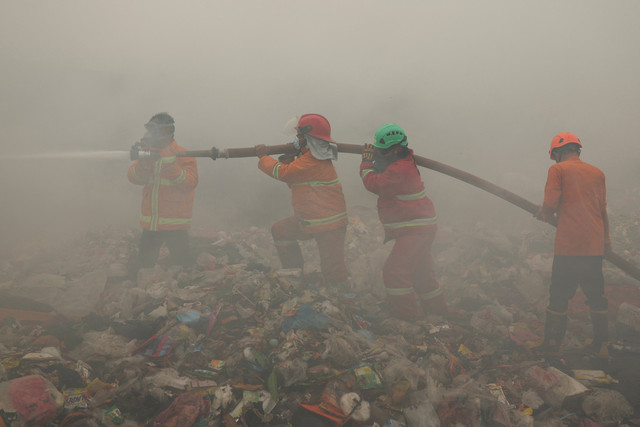 Petugas pemadam kebakaran berupaya memadamkan api saat asap mengepul dari sampah yang terbakar di lokasi TPA Jatiwaringin di Tangerang, Provinsi Banten, Indonesia, 1 Juli 2026. Foto: REUTERS/Ajeng Dinar Ulfiana
