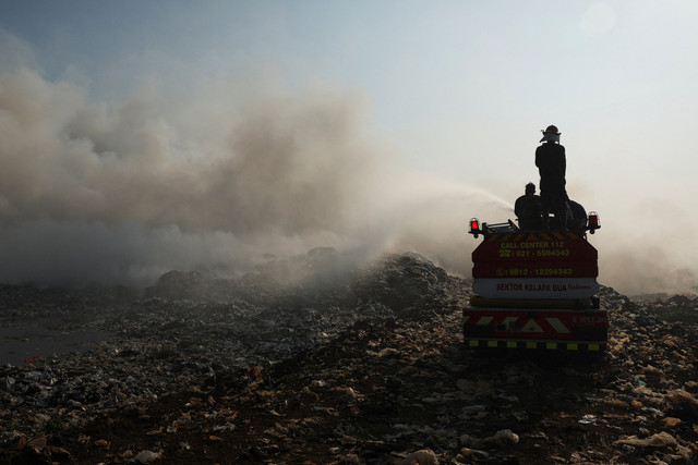 Petugas pemadam kebakaran berupaya memadamkan api saat asap mengepul dari sampah yang terbakar di lokasi TPA Jatiwaringin di Tangerang, Provinsi Banten, Indonesia, 1 Juli 2026. Foto: REUTERS/Ajeng Dinar Ulfiana