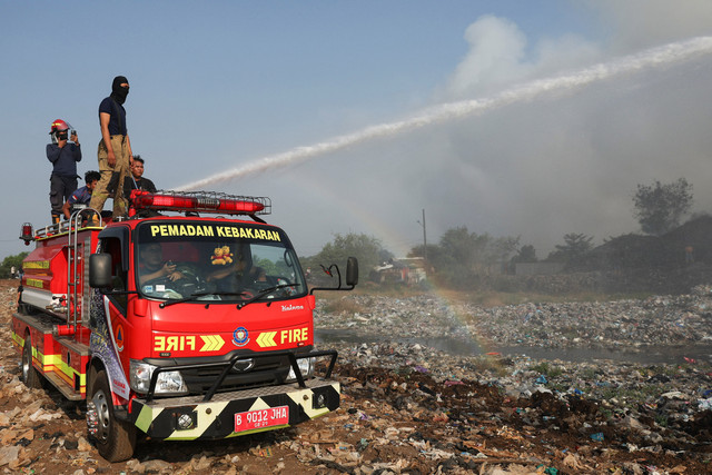 Petugas pemadam kebakaran berupaya memadamkan api saat asap mengepul dari sampah yang terbakar di lokasi TPA Jatiwaringin di Tangerang, Provinsi Banten, Indonesia, 1 Juli 2026. Foto: REUTERS/Ajeng Dinar Ulfiana