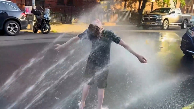 Seorang anak mandi air mancur dari hidran di pinggir jalanan New York, AS. Foto: Viory