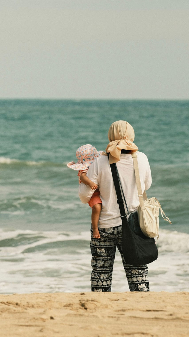 Ilustrasi Seorang Ibu dan anak kecil. Foto Pexelshttps://www.pexels.com/id-id/foto/laut-pantai-liburan-pasir-20209542/