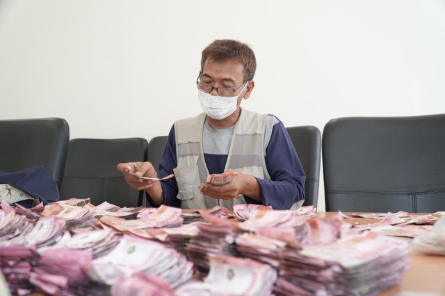 Petugas Bank Indonesia Tegal memeriksa uang Rp1,54 miliar milik warga Kabupaten Batang yang rusak terendam banjir rob. Foto: BI Tegal