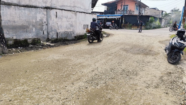 Pengendara melintasi jalan rusak yang diblokade emak-emak telah ditimbun pasir dan tanah. Akses jalan tersebut juga telah dibuka, Medan, Rabu (8/7). Foto: Amar Marpaung/kumparan