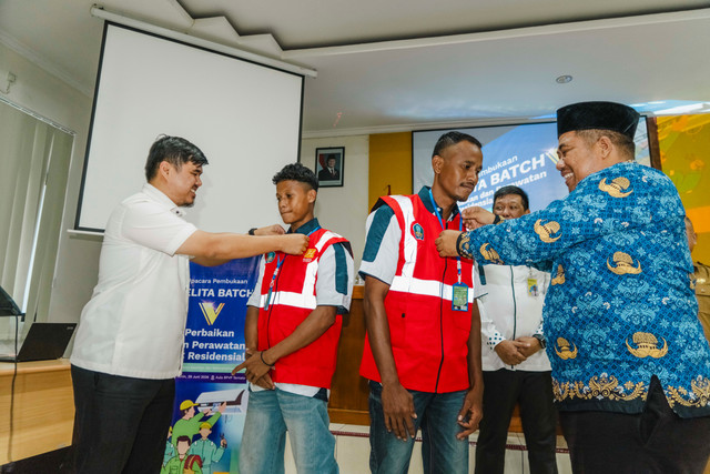 Community Development Manager Harita Nickel, Yuda Pranata dan Kepala Dinas Kepala Dinas Tenaga Kerja dan Transmigrasi Provinsi Maluku Utara, Marwan Polosiri mengalungkan ID Card kepada perwakilan peserta Pelita Batch 5. Foto: Dok. Istimewa
