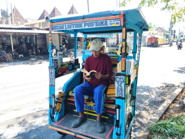 Sutopo (80) pegiat literasi di Yogyakarta memberikan bacaan gratis ke masyarakat melalui Becak Pustaka miliknya. Sutopo menjalini ini sejak 22 tahun lalu, dari becak kayuh hingga kini jadi becak listrik. Foto: Arfiansyah Panji Purnandaru/kumparan