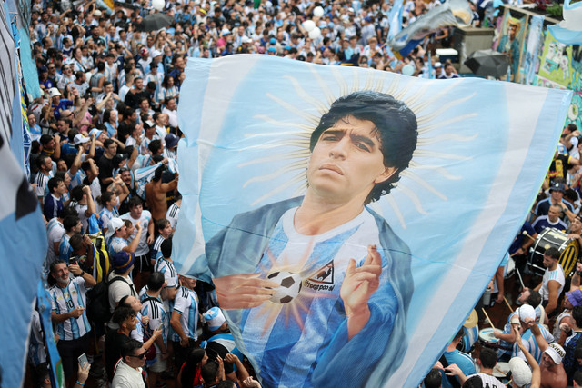 Para suporter Argentina berkumpul di sekitar spanduk besar yang menggambarkan Diego Maradona menjelang pertandingan Semifinal Piala Dunia FIFA 2026 antara Inggris vs Argentina di Atlanta, Georgia, AS, Selasa (14/7/2026). Foto: Amanda Perobelli/REUTERS