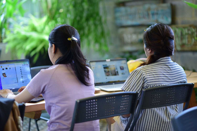 Dua wanita bekerja menggunakan laptop di ruang kantor modern dan hijau. (sumber: pexels.com)
