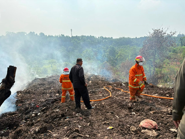 Petugas BPBD Kabupaten Bogor melakukan upaya pemadaman asap di lokasi penumpukan sampah di Cikeas, Bogor, Kamis (16/7). Foto: Nasywa Athifah/kumparan