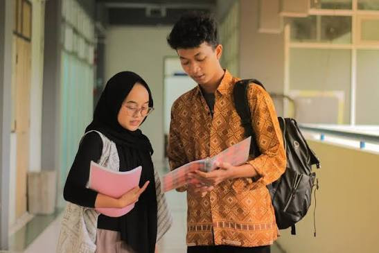 ilustrasi seorang mahasiswa/i yang sedang berdiskusi pelajaran di kampus