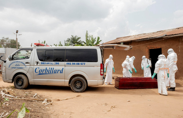 Anggota Perlindungan Sipil, tim berbasis komunitas lokal yang bekerja untuk membantu mengurangi penyebaran virus Ebola mendisinfeksi peti mati kayu yang berisi jenazah seorang pria tak dikenal akibat virus Ebola di Bunia, RD Kongo, (10/7/2026). Foto: Gradel Muyisa Mumbere/REUTERS