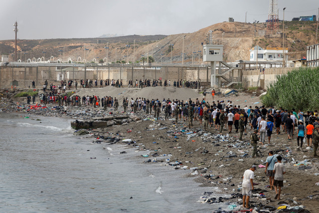 Orang-orang berjalan menuju perbatasan dengan Maroko meninggalkan Spanyol, di tengah penyeberangan massal migran dengan berjalan kaki dan melalui laut dari Maroko ke wilayah Spanyol, di Ceuta, Spanyol, Jumat (31/7/2026). Foto: Jon Nazca/REUTERS