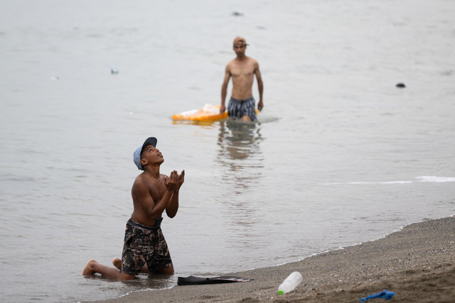 Seorang migran memberi isyarat di pantai di sekitar penghalang perbatasan dengan Maroko untuk memasuki wilayah Ceuta di Afrika Utara milik Spanyol, Jumat (31/7/2026). Foto: Jorge Guerrero/AFP