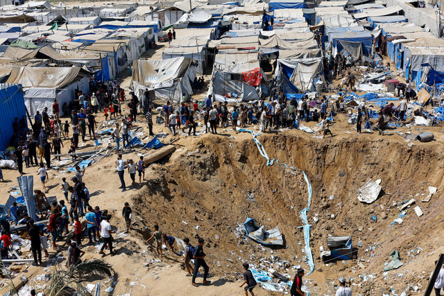 Warga Palestina berdiri di dekat kawah setelah serangan Israel terhadap gudang obat-obatan di Deir al-Balah, Jalur Gaza tengah, Sabtu (1/8/2026). Foto: Mahmoud Issa/REUTERS
