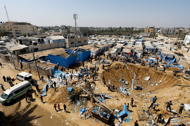 Warga Palestina berdiri di dekat kawah setelah serangan Israel terhadap gudang obat-obatan di Deir al-Balah, Jalur Gaza tengah, Sabtu (1/8/2026). Foto: Mahmoud Issa/REUTERS