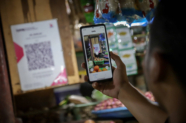 Pembeli menggunakan QRIS di pasar tradisional di Jakarta. Foto: Jamal Ramadhan/kumparan