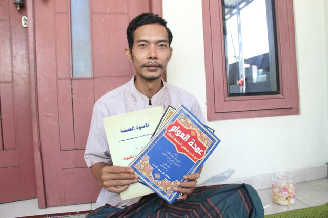 Supriyanto menunjukkan berbagai kitab di teras rumahnya yang berada di Desa Wates, Kecamatan Undaan, Kabupaten Kudus, Jawa Tengah pada Senin (3/8/2026). Foto: Vega Maarijil Ula/kumparan