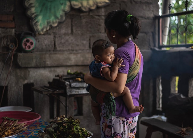 Seorang ibu menggendong anak di dapur rumahnya.(Foto: Artur I/Unsplash)