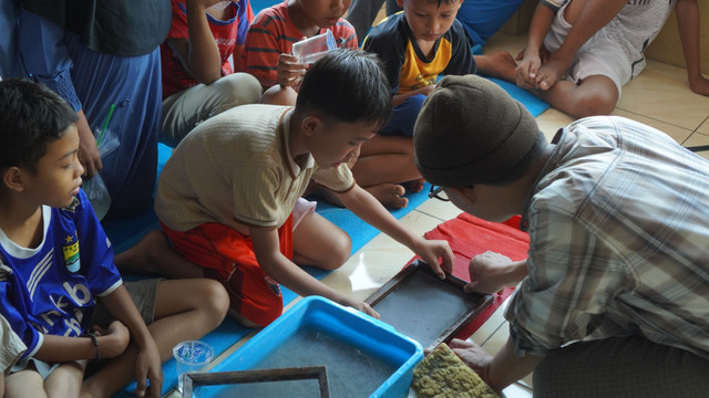 Anak-anak memperhatikan proses pencetakan bubur kertas saat workshop daur ulang kertas di Yayasan Oemah Daon, Desa Daon, Kecamatan Rajeg, Kabupaten Tangerang, pada Sabtu, 8 Agustus 2026. (Sumber: Dokumentasi pribadi)