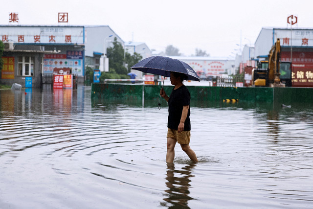 Warga berjalan melintasi banjir usai hujan deras akibat Topan Dolphin di Luohe, Provinsi Henan, China, Rabu (12/8/2026). Foto: Tingshu Wang/REUTERS
