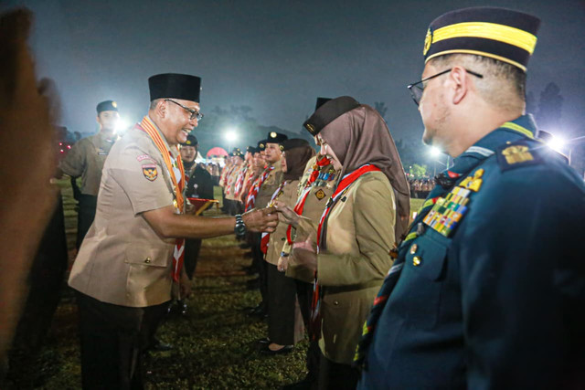 Ketua Kwarnas Gerakan Pramuka Kak Komjen Pol (Purn) Budi Waseso menyematkan tanda penghargaan Gerakan Pramuka Lencana Darma Bakti kepada Ketua Kwarcab Kota Pekanbaru Kak Sulastri pada Upacara Ulang Janji Peringatan Hari Pramuka di Cibubur. Foto: Dok. Diskominfo Pekanbaru