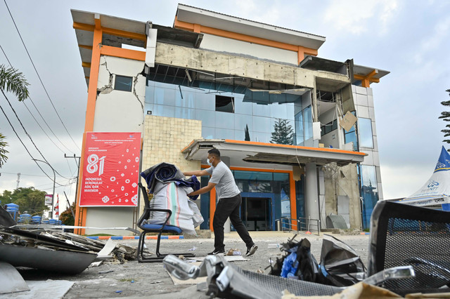 Pekerja memindahkan barang di dekat bangunan Bank NTT Kantor Cabang Ruteng yang mengalami kerusakan akibat gempa di Kabupaten Manggarai, NTT, Minggu (16/8/2026). Foto: Fikri Yusuf/ANTARA FOTO