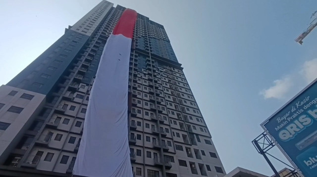 Tim Dinas Pemadam Kebakaran dan Penyelamatan Kota Depok membentangkan bendera Merah Putih berukuran 10 x 120 meter dari lantai 37 Apartemen Envesio, Senin (17/8/2026). Foto: Dok. Istimewa