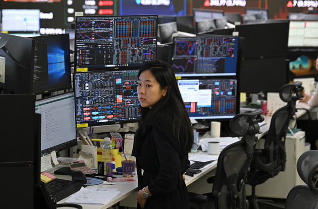 Petugas transaksi mata uang memantau layar indeks saham di ruang perdagangan Hana Bank, Seoul, Korea Selatan (21/7/2026). Foto: Jung Yeon-je/AFP