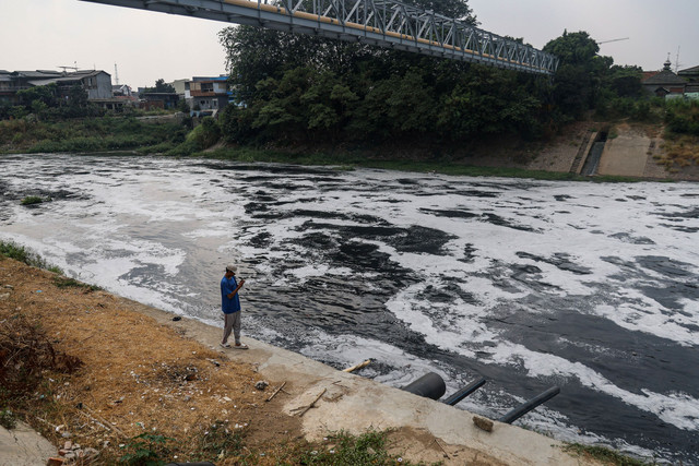 Warga melintas di bantaran Kali Bekasi yang berbusa dan berwarna hitam diduga tercemar limbah pabrik di kawasan Margahayu, Kota Bekasi, Jawa Barat, Kamis (20/8/2026). Foto: Darryl Ramadhan/ANTARA FOTO