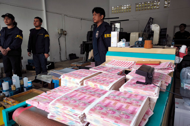 Petugas kepolisian berada di dekat tumpukan uang palsu saat melakukan penggerebekan di Taman Tekno Bumi Serpong Damai (BSD), Serpong, Tangerang Selatan, Banten, Sabtu (22/82026).  Foto: Muhammad Iqbal/ANTARA FOTO