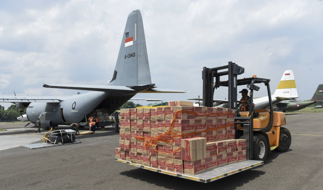 Petugas memasukkan logistik bantuan ke pesawat angkut militer milik TNI AU di Lanud Halim Perdanakusuma (Sumber: Kumparan)