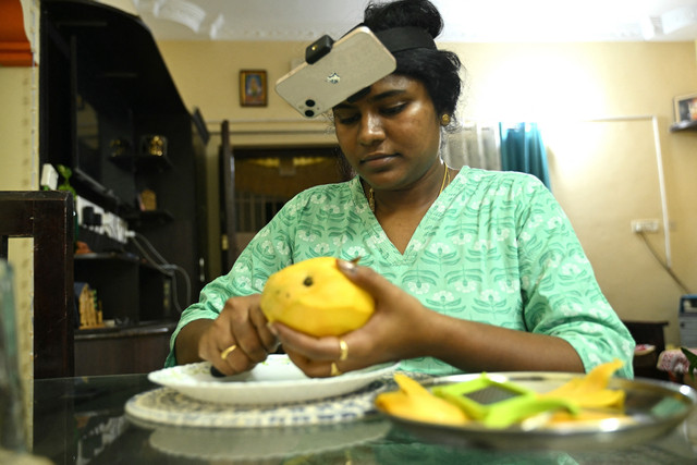 Ibu rumah tangga asal India, Nagireddy Sriramyachandra, mengenakan ponsel pintar di kepalanya untuk merekam aktivitasnya melalui teknik perekaman gerak (motion capture) di rumahnya di Chennai, India, Jumat (15/5/2026). Foto: R.Satish BABU/AFP