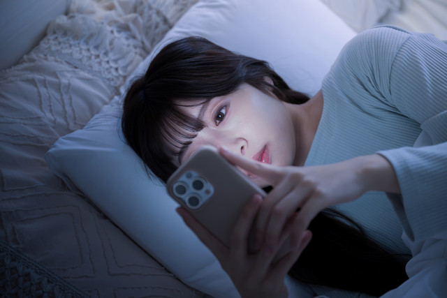 Ilustrasi wanita tidur melihat handphone. Foto: kapinon.studio/Shutterstock