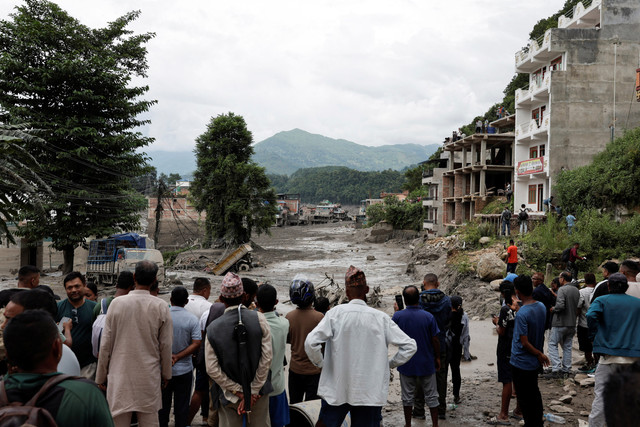 Warga berdiri di dekat rumah-rumah yang tertutup lumpur dan jalan, setelah banjir bandang di Trishuli, distrik Nuwakot, Nepal, Rabu (26/8/2026). Foto: Navesh Chitrakar/REUTERS