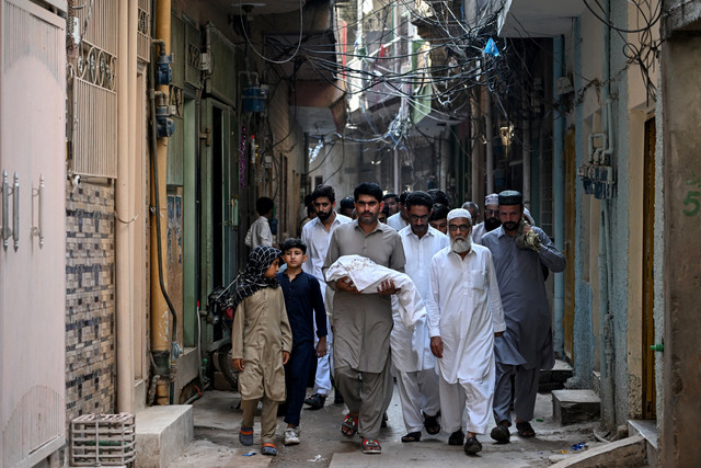 Seorang pria membawa jenazah bayi yang menjadi korban tewas kebakaran di luar bangsal Kesehatan Ibu dan Anak (MCH) di Rumah Sakit Pakistan Institute of Medical Sciences (PIMS) saat prosesi pemakaman di Rawalpindi, Pakistan, Rabu (26/8/2026). Foto: Aamir Qureshi / AFP