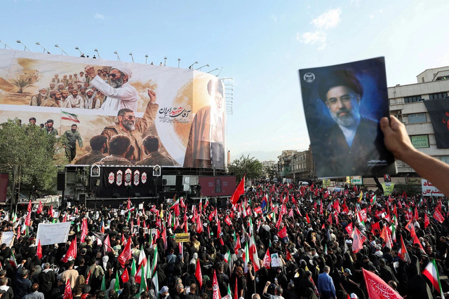 Seorang pelayat memegang gambar Pemimpin Tertinggi Iran Mojtaba Khamenei saat warga berkumpul untuk prosesi pemakaman mendiang Pemimpin Tertinggi Iran Ayatollah Ali Khamenei, yang tewas pada 28 Februari dalam serangan udara Israel dan AS, di Teheran, Foto: REUTERS/Mohammed Salem